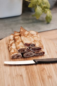 Delicious and fresh pancakes with strawberry sauce on the wooden board in the kitchen.