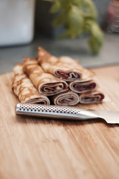 Delicious and fresh pancakes with strawberry sauce on the wooden board in the kitchen.