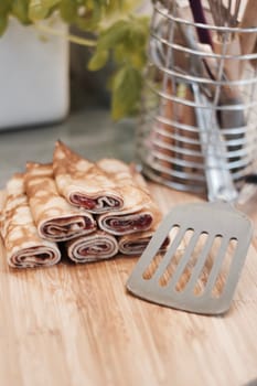 Delicious and fresh pancakes with strawberry sauce on the wooden board in the kitchen.