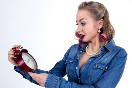 Frightened young woman in curlers with alarm clock