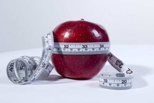 concept image of a tape measure around a red apple