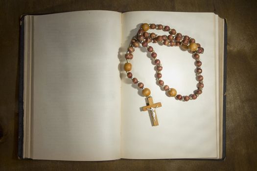 Open book with a rosary on the wooden table