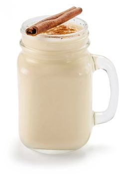 Homemade eggnog with cinnamon in mason jar isolated on white. Eggnog with spices - cinnamon and cinnamon stick in jar