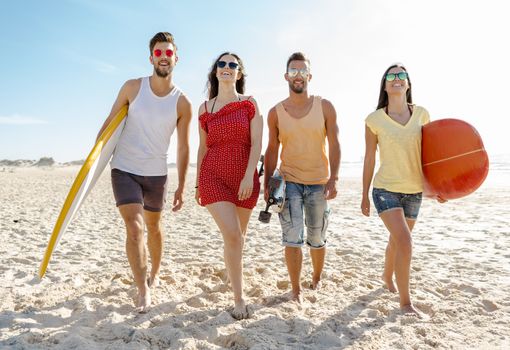 Friends walking together at the beach and holding surfboards