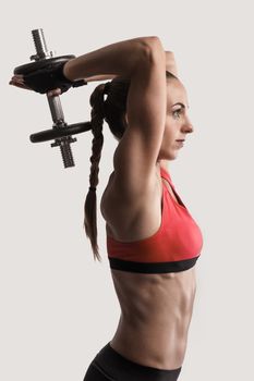 Beautiful young woman in a workout gear lifting dumbbells