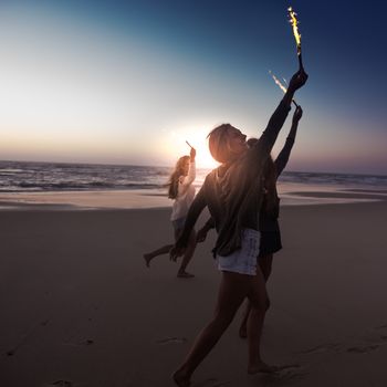 Teenage friends running on a beach with fireworks