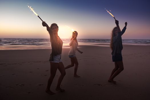 Teenage friends running on a beach with fireworks
