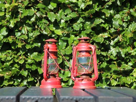 Two Red Rusty Lanterns on Black Table Outside