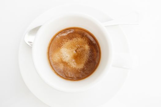 Top view of espresso coffee in white cup on white table. High key style shot.