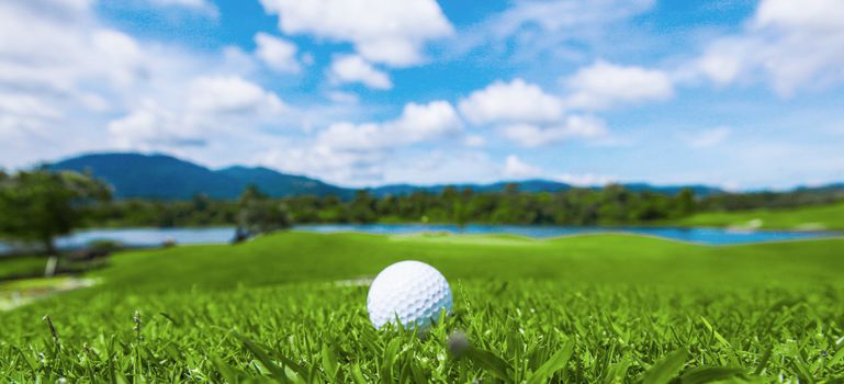 Golf ball on course, beautiful landscape with mountains on background