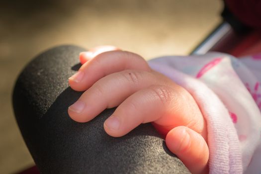 A babies hand resting on the bar across a pushchair in the united kingdom