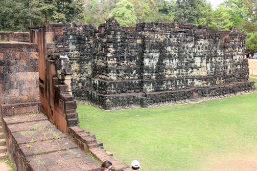 Brick and stone masonry of the ancient walls of the Cambodian temple, with reliefs and sculptures, pillars and columns on a natural background