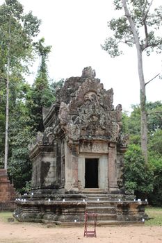 Brick and stone masonry of the ancient walls of the Cambodian temple, with reliefs and sculptures, pillars and columns on a natural background