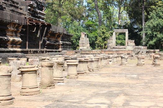 Brick and stone masonry of the ancient walls of the Cambodian temple, with reliefs and sculptures, pillars and columns on a natural background