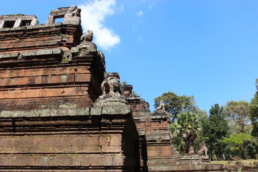 Brick and stone masonry of the ancient walls of the Cambodian temple, with reliefs and sculptures, pillars and columns on a natural background