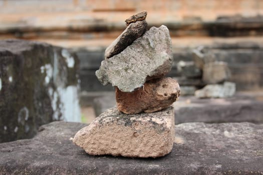 a small pyramid of stones on the background of the ruins of an ancient temple