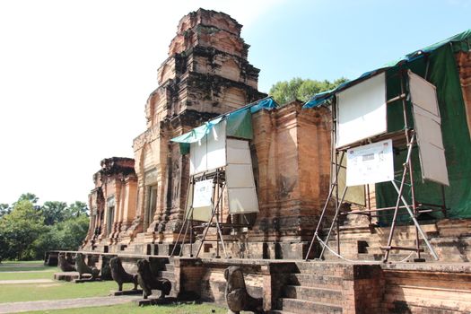 Brick and stone masonry of the ancient walls of the Cambodian temple, with reliefs and sculptures, pillars and columns on a natural background