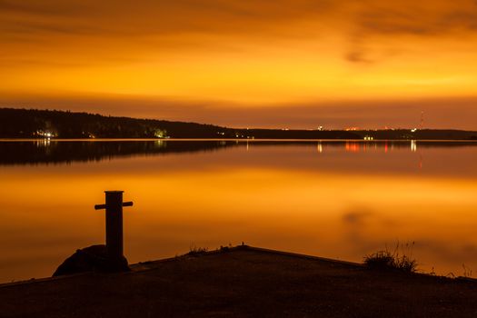 Strip of a city landscape over a pond in the evening in twilight