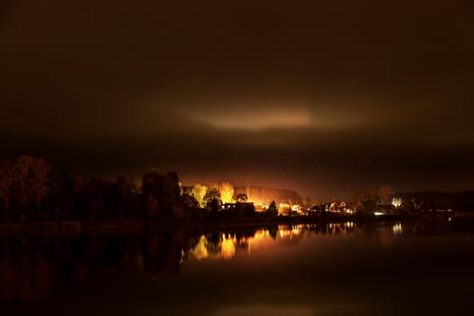 Strip of a city landscape over a pond in the evening in twilight