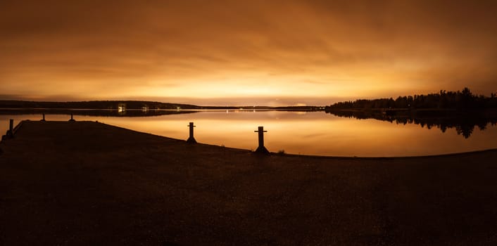 Strip of a city landscape over a pond in the evening in twilight