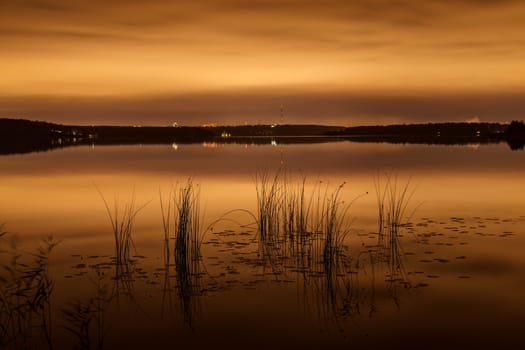 Strip of a city landscape over a pond in the evening in twilight