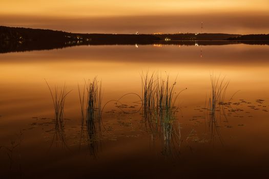 Strip of a city landscape over a pond in the evening in twilight