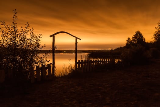 Night landscape. A fence before a pond and the night city on the horizon