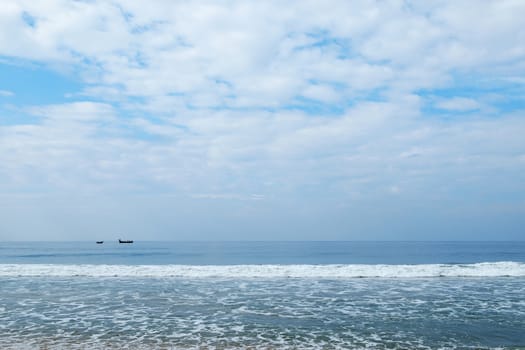 Indian Ocean in calm weather with clouds and small boats on a horizon