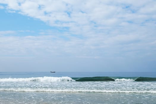 Indian Ocean in calm weather with small waves and clouds. small boats on the horizon