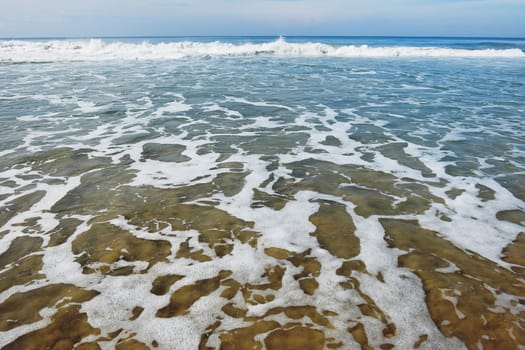 Indian Ocean in calm weather with small waves and many foam