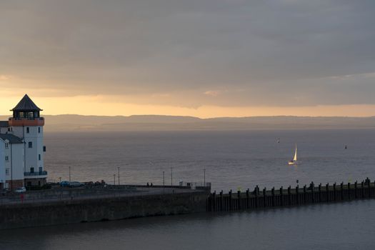 a yacht catches last rays of sun on return to harbour. Portishead