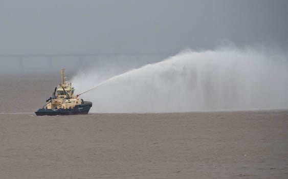 a tug tests fire pump hoses for sea rescues of shipping on fire.