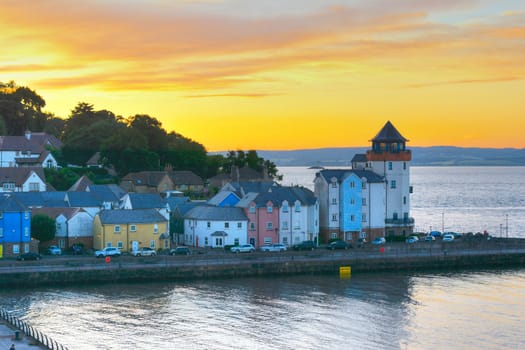 The setting sun glows yellow over an estuary jetty