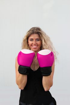 funny blonde girl in black casual dress in red boxing gloves