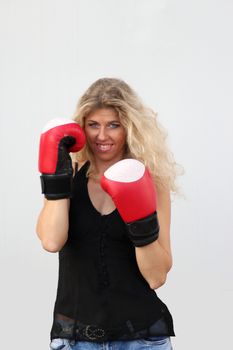 funny blonde girl in black casual dress in red boxing gloves