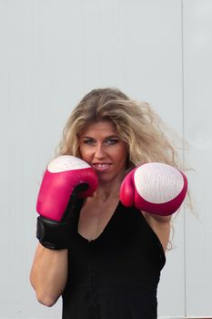 funny blonde girl in black casual dress in red boxing gloves