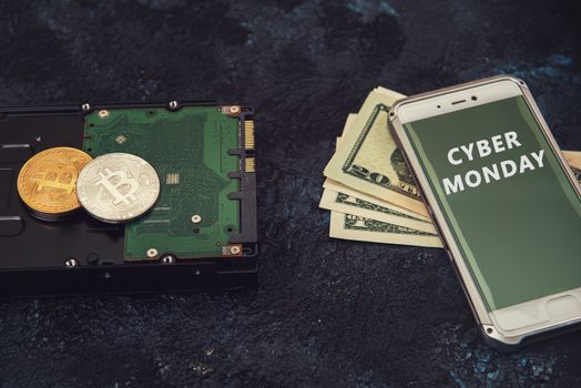 Bitcoin coins on the HDD and phone with Cyber Monday sign