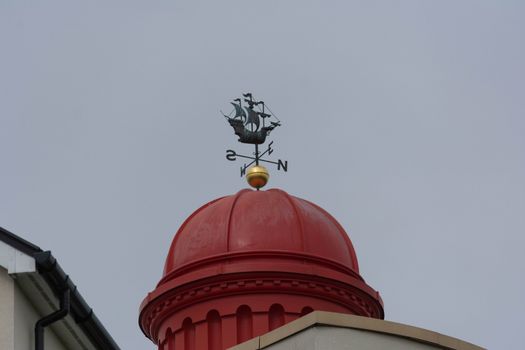 a metal weathervane in the shape of a galleon on a pagoda rooftop