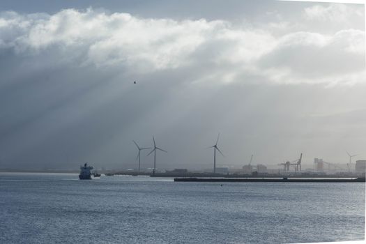 a cargo ship approaches Avonmouth dock with wind turbines in background