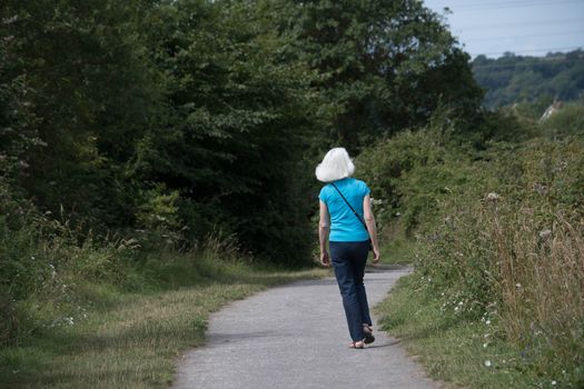 a blonde woman walks a countryside path