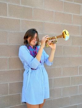 Female jazz trumpet player with her horn outside.