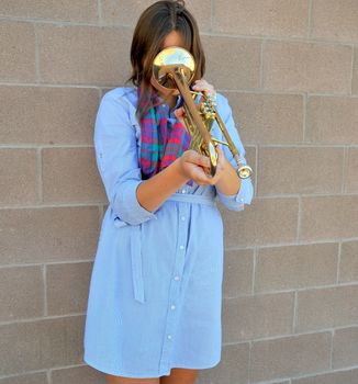 Female jazz trumpet player with her horn outside.