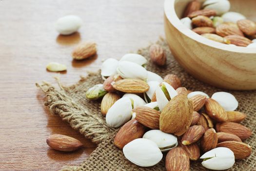 Almond mixed on sack with wooden background.