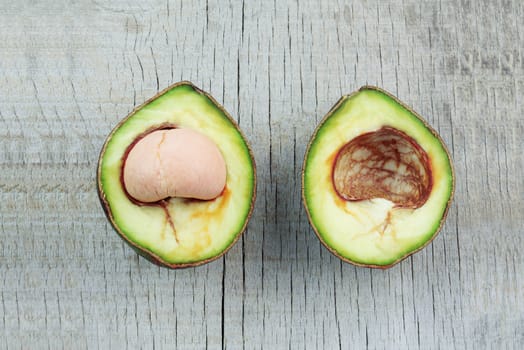 Raw avocado cut of half on a wooden floor.