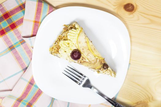 slice of delicious homemade cake with coffee cream decorated by red grape and pears on white plate  on wood table