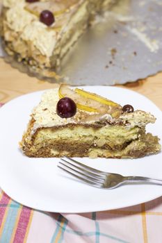 slice of delicious homemade cake with coffee cream decorated by red grape and pears on white plate  on wood table