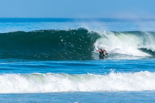 Bodyboarder in action on the ocean waves on a sunny day.