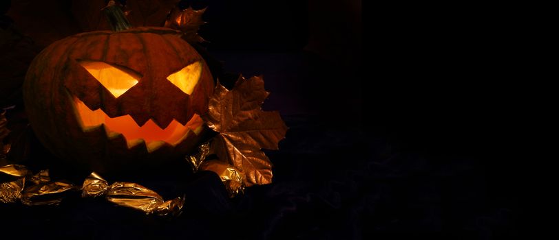 Halloween pumpkin with autumn leafs on black