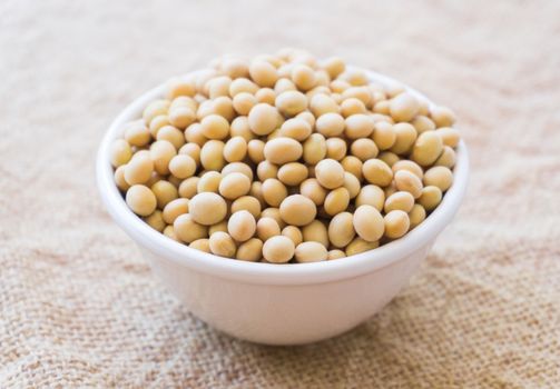Closeup soy beans on white bowl with sackcloth background , healthy food concept