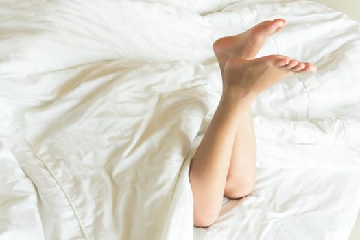 Woman legs relax on the bed after waking in the morning, selective focus